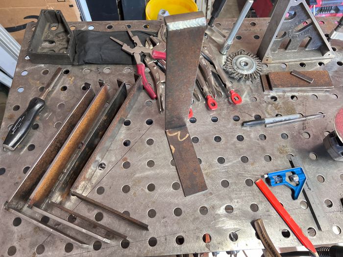 Shelf bracket parts laid out on the welding table