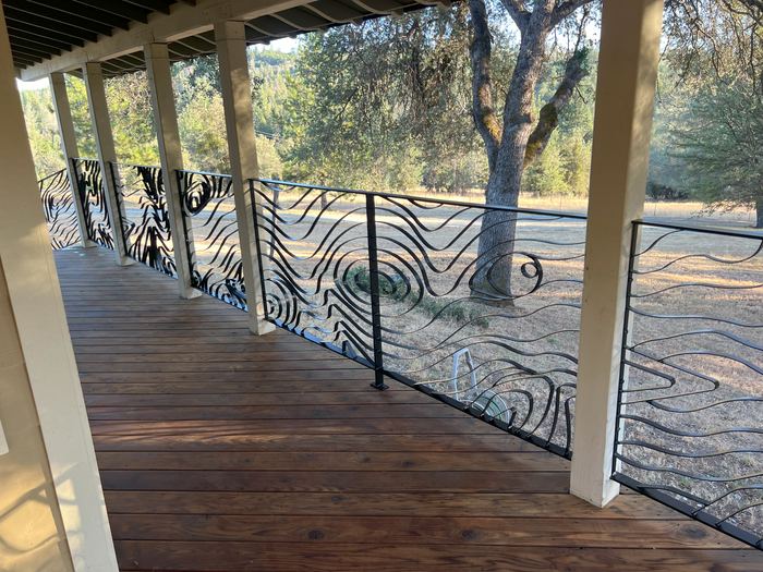 Long run of Topograin railing along a covered porch with a wood-knot form